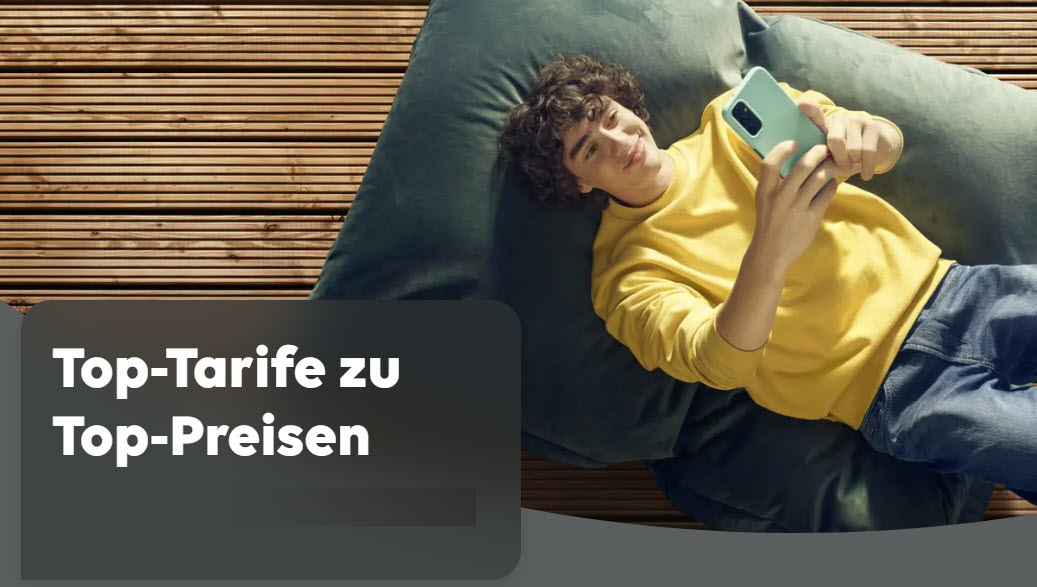 Top Tarife bei EWE Dekoratives Bild. Ein junger Mann liegt auf einem bequemen Bodenkissen und schaut freudig auf sein Handy in der Hand. Im Hintergrund ein brauner Holzfußboden.
